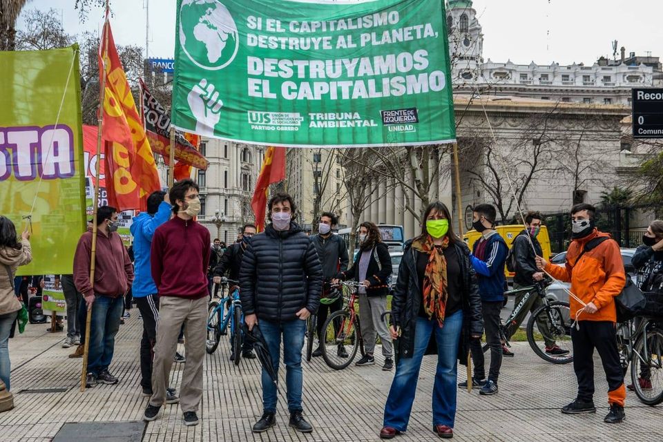 La imagen puede contener: 1 persona, exterior, texto que dice "RANCC SIELCAPITALISMO TALISMO DESTRUYE AL PLANETA, DESTRUYAMOS EL CAPITALISMO TRIBUNA AMBIENTAL UNIDAD PARTID BRERO TAN Reco Comu"