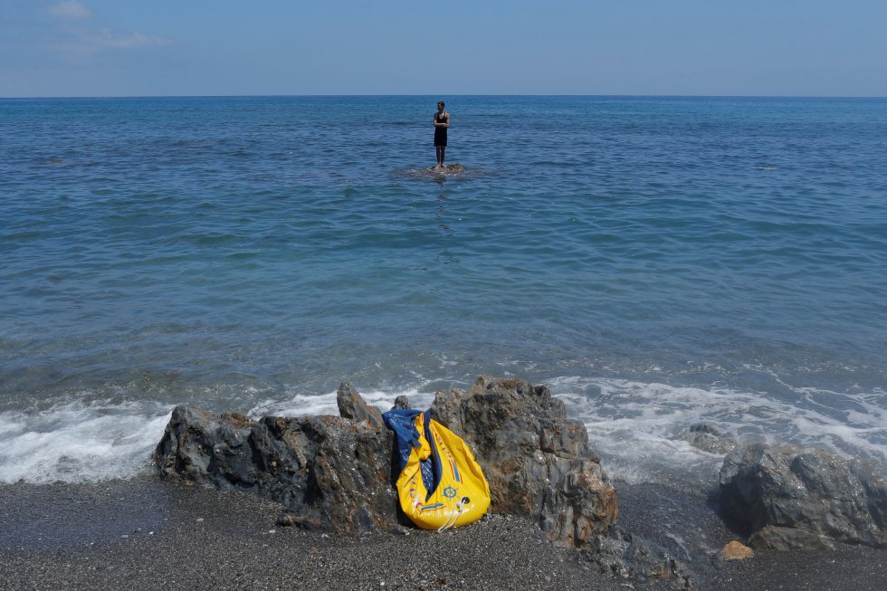 Un joven permanece subido a una roca frente a la playa del Tarajal, en la frontera de Ceuta. La llegada de personas a nado y a pie ha sido constante durante todo el lunes y contin&uacute;a en la ma&ntilde;ana de este martes en la misma playa donde se han desplegado tanques.