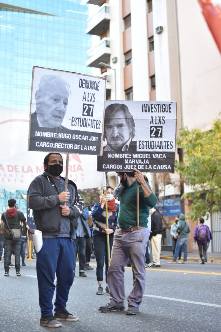 Puede ser una imagen de 2 personas, personas de pie, calle y texto que dice "DENUNCIE ALXS 27 ESTUDIANTES NOMBRE:HUGO OSCAR JURI CARGO:RECTOR DE LA UNC INVESTIGUÃ ALXS 27 ESTUDIANTES NOMBRE: MIGUEL VACA NARVAJA CARGO: JUEZ DELA LA CAUSA DELAM ERTALD NTAD RTO RIA"